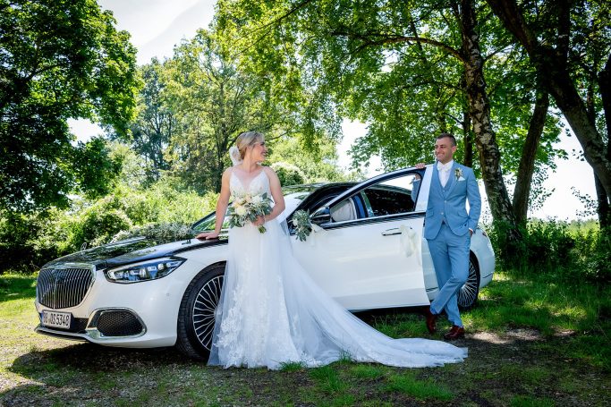 Paar steht zusammen an einem Auto, lächelt herzlich