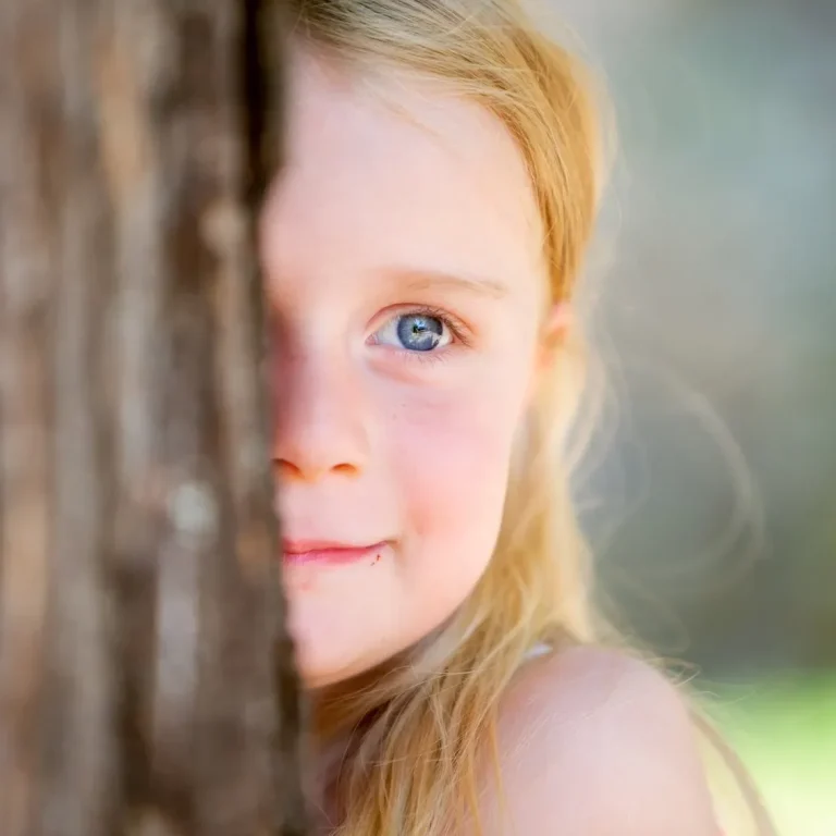 Kitakind lächelt an einem Baum.