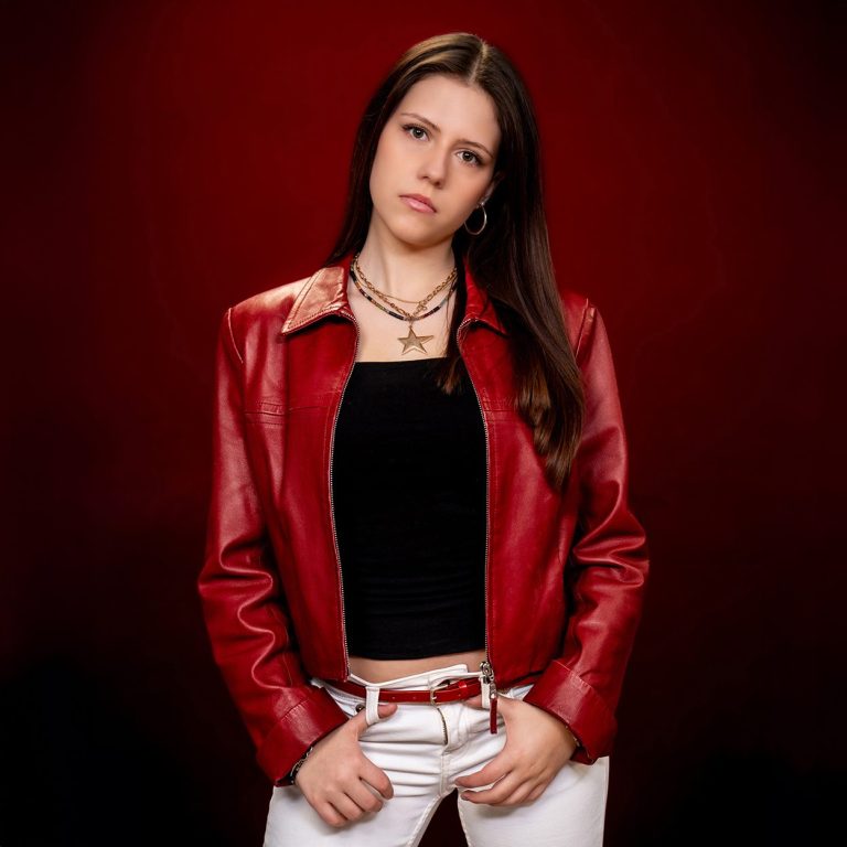 Junge Frau in roter Lederjacke sieht cool in die Kamera.